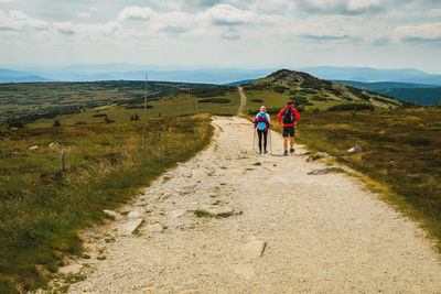 Rear view of couple walking on mountain against sky