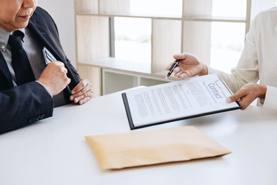 Midsection of man holding paper with text on table