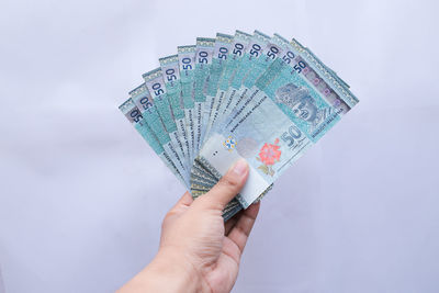 Close-up of hand holding umbrella against white background