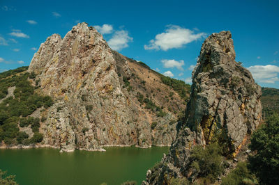 Rock formation by lake against sky