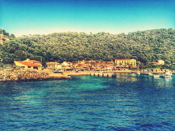 Scenic view of river by houses against clear blue sky