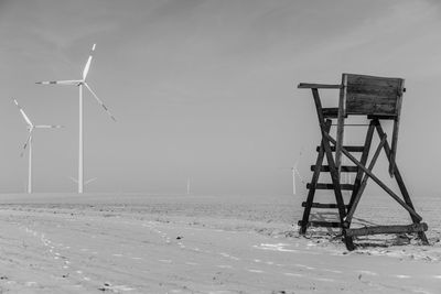 Wind turbines on field against sky