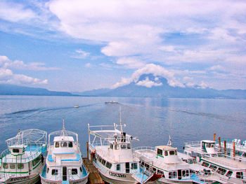 Sailboats moored at harbor against sky