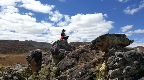 View of rocks on cliff against cloudy sky