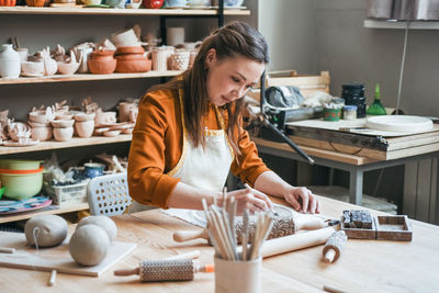 Middle-aged woman moulding a plate in a pottery studio