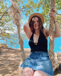 Portrait of smiling young woman sitting on swing