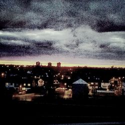 Illuminated cityscape against cloudy sky