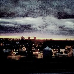 Illuminated cityscape against cloudy sky