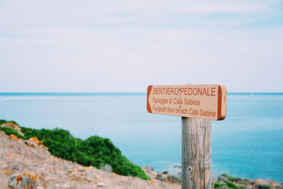 Information sign on cliff against sea