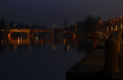 Illuminated bridge over river in city at night
