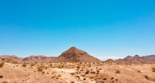 Scenic view of arid landscape against clear blue sky