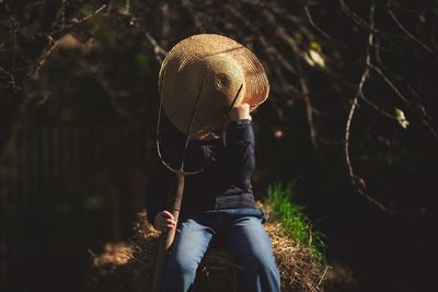 Rear view of man sitting by tree in forest