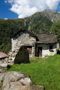 House on field by mountains against sky