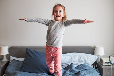 Cute girl standing on bed at home