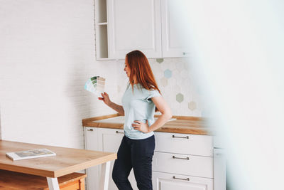 Full length of woman standing against white wall at home