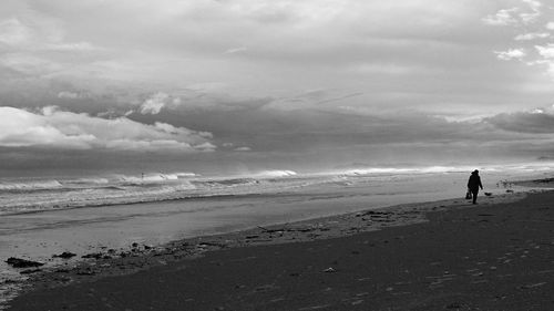 People walking on beach against sky