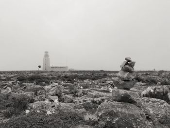 Lighthouse on rock amidst buildings against sky