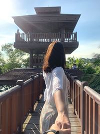 Woman sitting on railing against sky