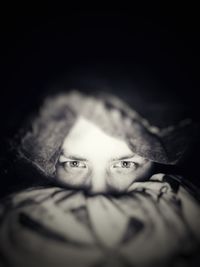 Close-up portrait of young woman against black background