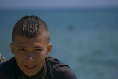 Portrait of boy standing against sea during sunny day