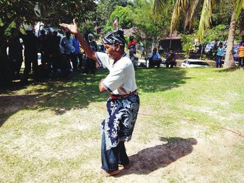 Crowd looking at senior man dancing on grassy field