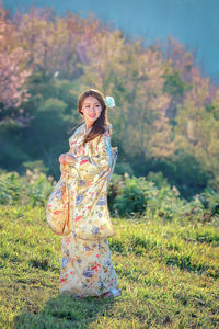 Portrait of smiling young woman standing on field