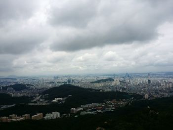 Aerial view of cityscape against cloudy sky