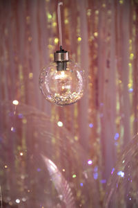 Close-up of illuminated light bulbs hanging on glass
