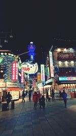 People walking on illuminated street at night