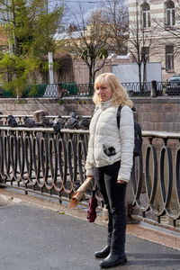 Full length of woman standing on sidewalk in city