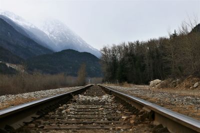 Railroad track by mountain against sky