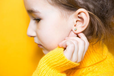 Close-up girl looking away against yellow background