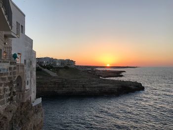 Scenic view of sea against buildings during sunset