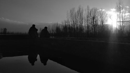 Rear view of silhouette people walking on lake