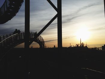 Silhouette bridge against cloudy sky