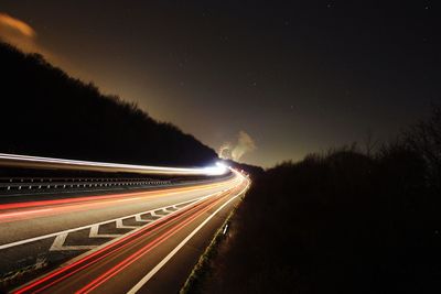 Light trails on road against sky at night