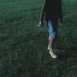 Low section of man walking on grassy field