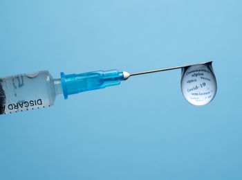 Close-up of syringe against blue background
