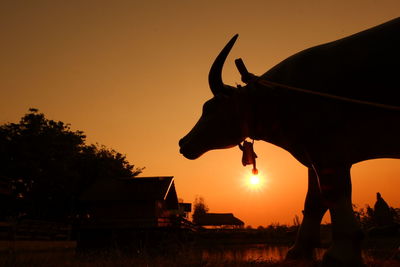 Silhouette of statue against orange sunset sky