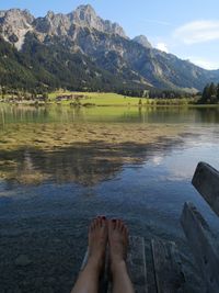 Low section of woman on bench against lake