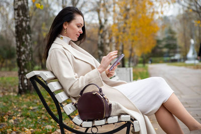 Side view of woman using mobile phone in park