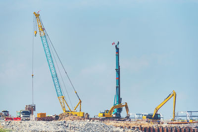 Low angle view of cranes against sky