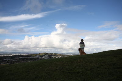 Rear view of boy standing on field against sky