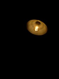 Close-up of illuminated light bulb over black background