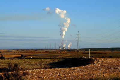 Smoke emitting from chimney on field against sky