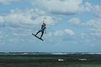 Low angle view of man jumping on beach against sky