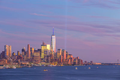 City at waterfront against cloudy sky