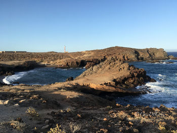 Rocks on beach against clear sky