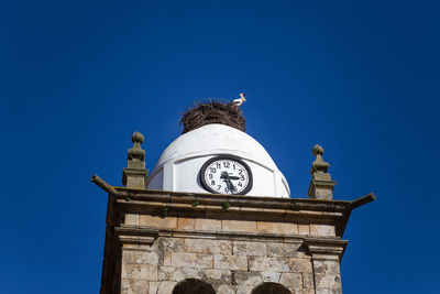 Low angle view of clock tower against blue sky