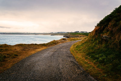 Scenic view of road by sea against sky